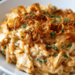 Creamy French Onion Chicken Orzo Casserole baked with cheese and crispy fried onions in a white casserole dish.