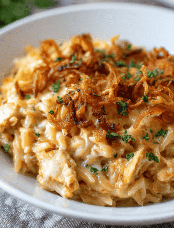 Creamy French Onion Chicken Orzo Casserole baked with cheese and crispy fried onions in a white casserole dish.