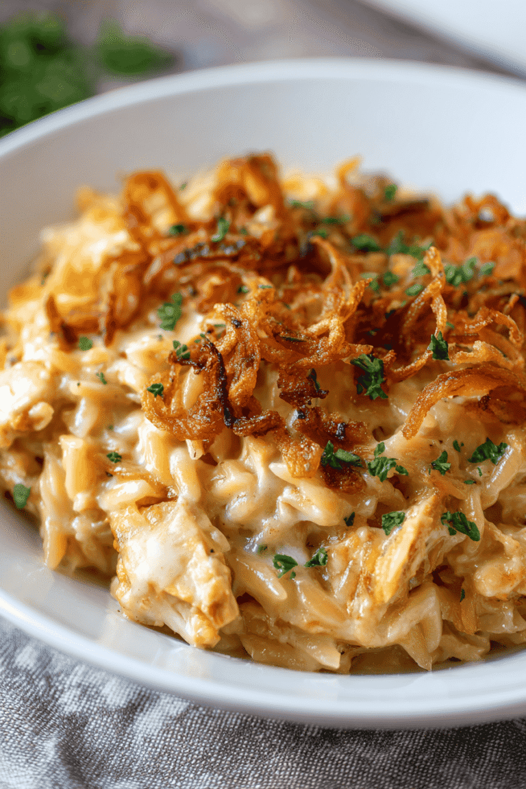 Creamy French Onion Chicken Orzo Casserole baked with cheese and crispy fried onions in a white casserole dish.