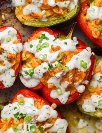 Dairy-free buffalo chicken stuffed bell peppers garnished with fresh herbs on a white plate