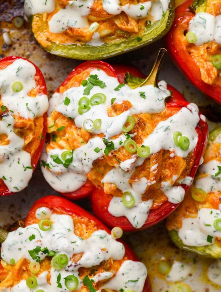 Dairy-free buffalo chicken stuffed bell peppers garnished with fresh herbs on a white plate