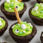 A close-up of Easy Cauldron Cookies decorated with candy, marshmallows, and pretzel sticks for Halloween.