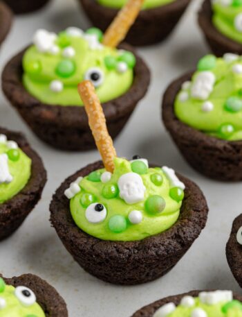 A close-up of Easy Cauldron Cookies decorated with candy, marshmallows, and pretzel sticks for Halloween.