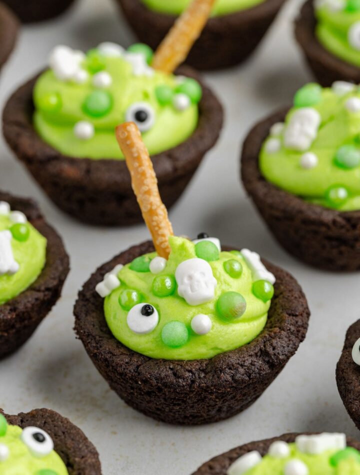A close-up of Easy Cauldron Cookies decorated with candy, marshmallows, and pretzel sticks for Halloween.