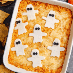 Halloween Buffalo Chicken Dip with spiderweb sour cream design served in pumpkin bowl