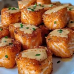 Crispy Bang Bang Salmon Bites topped with spicy creamy sauce served on a white plate with fresh herbs.